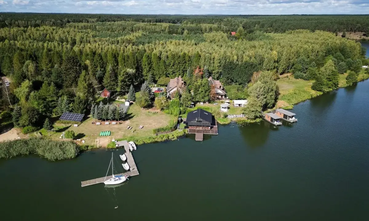 Widok z lotu ptaka na jezioro, las i domki nad wodą.