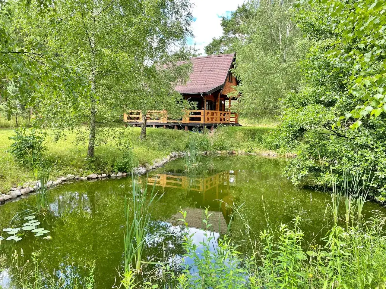 Wędkarz nad jeziorem z domkiem w tle